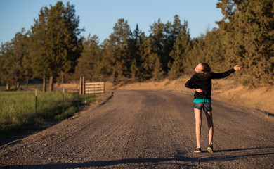 Young girl dances outside on a country dirt road