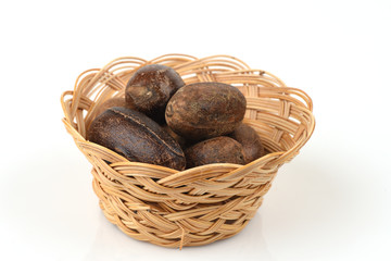 Nutmeg, spices, medicinal properties in a basket on a white background.