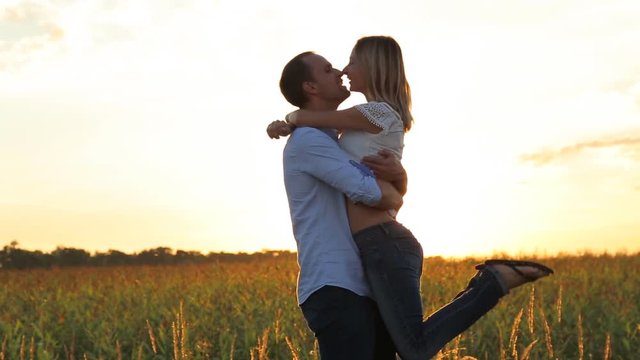 Romantic young couple is kissing on a sunset with sun shining bright behind