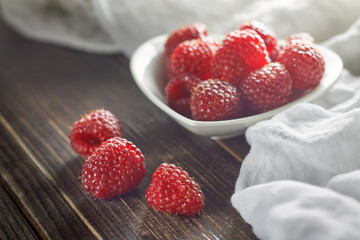 Red raspberries in white bowl on wooden surface