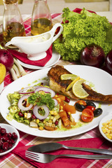 Fried scorpaena scrofa with salad on the plate and serving at the table with fresh vegetables, sauce and cutlery.