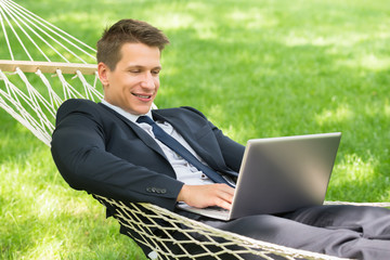 Man Lying In Hammock Using Laptop