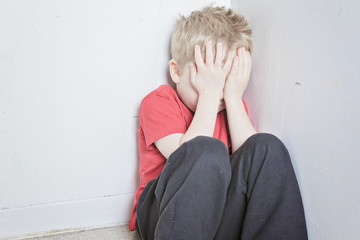 Neglected lonely child leaning at the wall