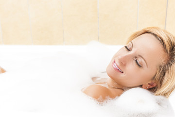 Obraz na płótnie Canvas Portrait of Sexy Caucasian Blond Female Relaxing in Foamy Bathtub