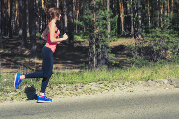 Young fitness woman running on forest trail. Runner athlete jogg
