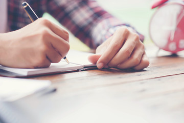 Hand writing in notebook  coins and alarm clock for background