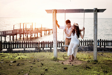 Sweet young couple on a swing with a sea view