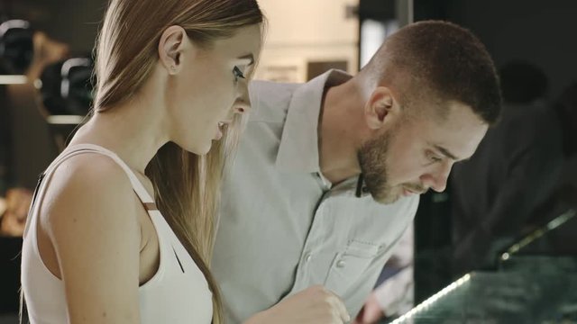 Young beautiful couple choosing wedding ring in jewelry shop