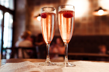 Two glasses of champagne with raspberry on a table in a cafe