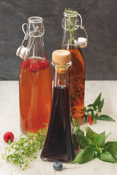 Assorted bottles of vinegar. Different kinds of vinegar in various bottles arranged with fruits, herb and hot pepper