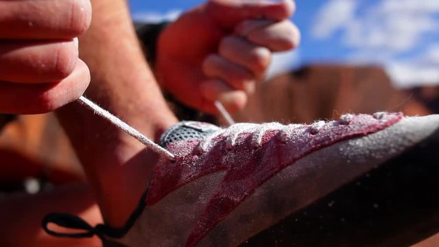 Person tying shoelace, to get ready to go climbing.