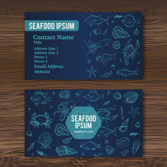 Business card template with hand drawn doodle seafood icons for restaurant. Vector illustration. Cartoon fresh sea food symbols: fish, crab, lobster, oyster, shrimp, shellfish on wood background.
