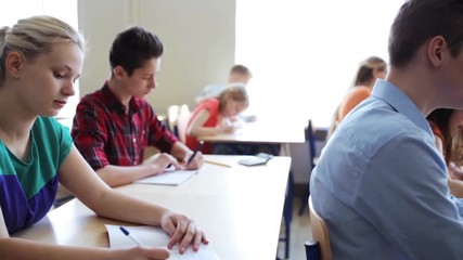 students with notebooks writing test at school
