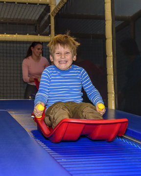 kleiner Junge hat Spass auf Rollschlittenbahn im Indoor-Freizeitpark 