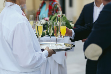 Guests in black suits take glasses of champagne from a tray
