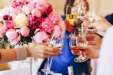 Guests clang glasses of champagne and whisky before a pink bouqu