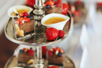Ripe strawberries lie on the steel dish with sweets
