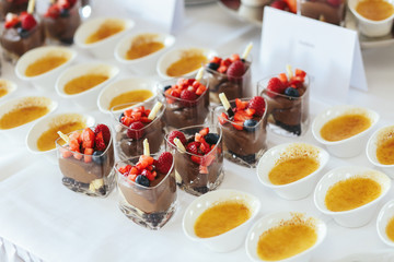 Little bowls with tasty sauce surrounded glasses with chocolate