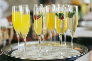 Champagne flutes with strawberries and juice stand on the steel