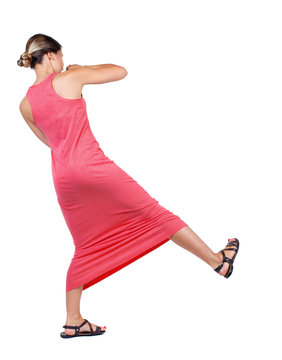 skinny woman funny fights waving his arms and legs. Isolated over white background. A slender woman in a long red dress swinging leg