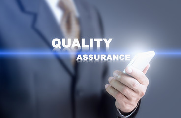Businessman pressing hand quality assurance word on virtual screen. Can bring to the medium of your...