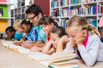 Teacher and kids reading book in library