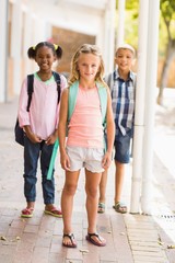 Fototapeta premium Smiling school kids standing in school corridor with arm around