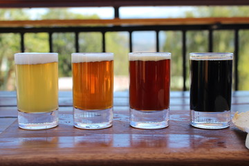 A selection of four different craft beers on a wooden board