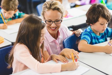 Obraz premium Teacher helping girl with their homework in classroom