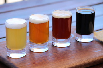 A selection of four different craft beers on a wooden board