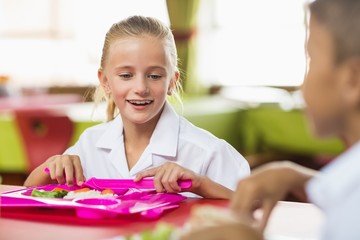 Fototapeta premium Schoolgirl having lunch during break time in school cafeteria