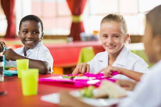 Children having lunch during break time in school cafeteria - Powered by Adobe