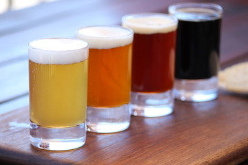 A selection of four different craft beers on a wooden board