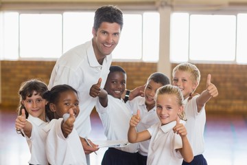 Portrait of sport teacher and students showing thumbs up