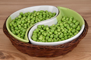Green peas in ceramic bowls and wicker basket