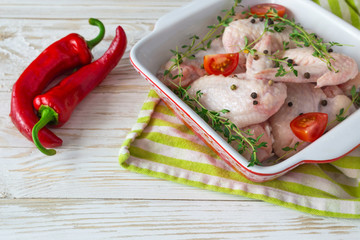 Raw chicken wings with thyme, chili, pepper and tomatoes
