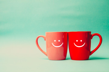 Two cups of coffee and stand together with smile face on cup.