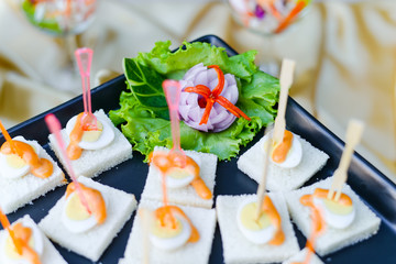 Sandwiches and boiled eggs with sauce on black plate for serve in party cocktail