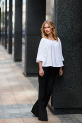 Business woman in full growth leaned on modern building