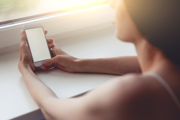 Brunette woman sitting at the window with mobile phone