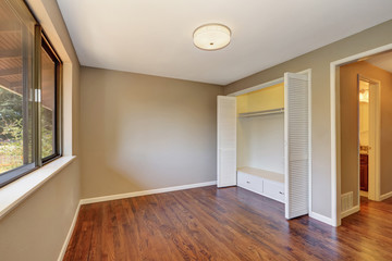 Empty beige room with closet and hardwood floor.