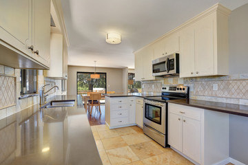 Kitchen interior with tile back splash trim and tile flooring.