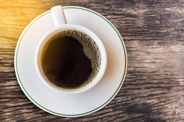 top view  hot coffee cup with bubbles on wooden table in the morning