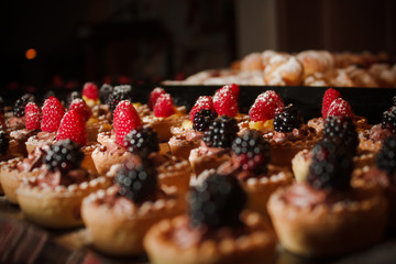 Dessert dolce fatto di cestini di pasta ripieni di mousse al cioccolato e decorate con i lamponi e more.