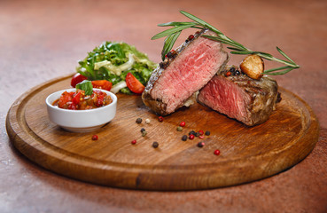 sliced veal steak medium rare with salsa sauce and salad on a ci