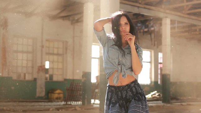 Woman with a beautiful figure dancing in the dust and sun