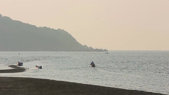 Misty tropical seascape with boats and fishermen silhouettes