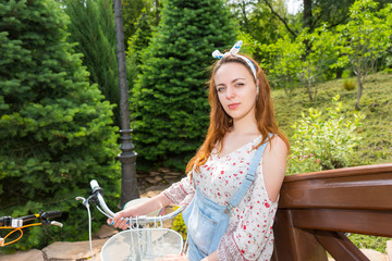 Young romantic female standing near her bicycle and smiling