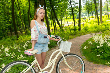 Fasionable female with her bicycle standing on a footpath in a p