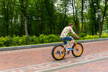 Young man riding a bike on a footpath in a park